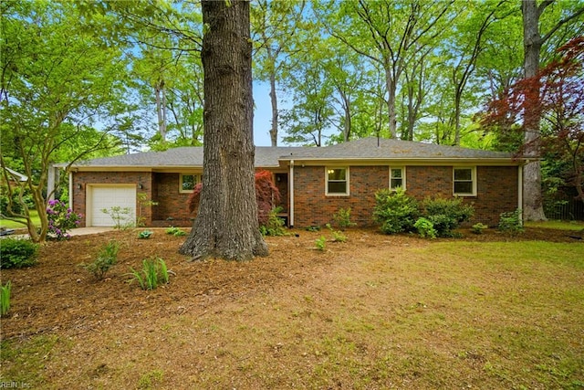 view of front of house featuring an attached garage, brick siding, and a front lawn