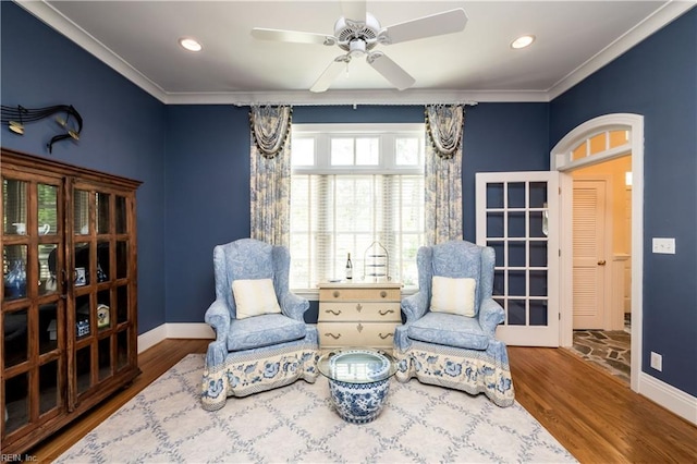 sitting room featuring crown molding, baseboards, a ceiling fan, and wood finished floors