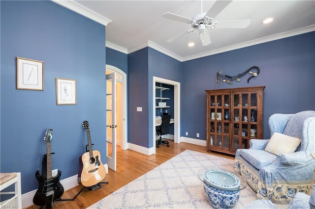 sitting room featuring baseboards, a ceiling fan, wood finished floors, and arched walkways