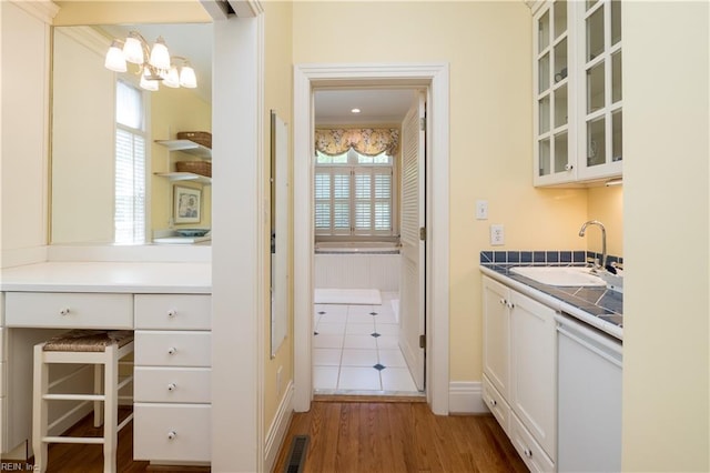 interior space featuring a sink, a chandelier, dishwasher, baseboards, and visible vents