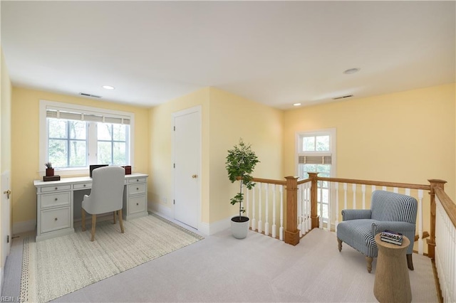 office featuring a wealth of natural light, visible vents, and light carpet