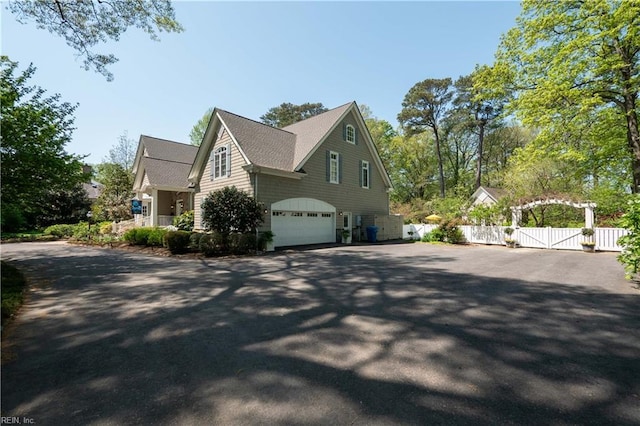 view of side of property featuring a gate, driveway, fence, and a garage