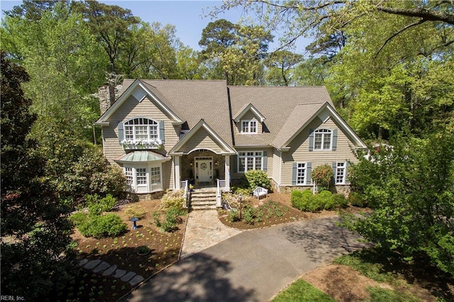 view of front facade featuring a chimney and a shingled roof