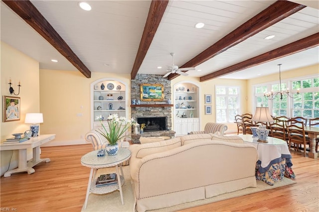 living area featuring ceiling fan with notable chandelier, a wealth of natural light, a fireplace, and light wood-type flooring
