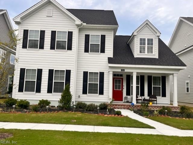view of front of house featuring a shingled roof, a front yard, and covered porch