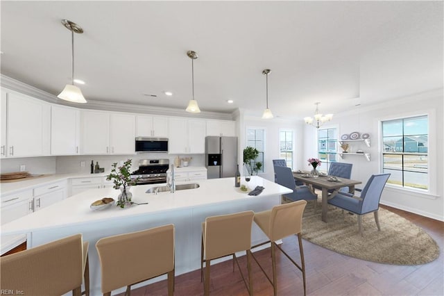 kitchen with white cabinets, a kitchen breakfast bar, stainless steel appliances, a sink, and a notable chandelier