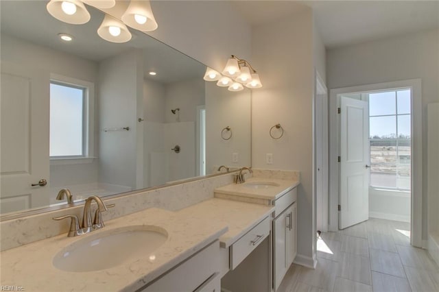 bathroom featuring a chandelier, double vanity, a shower, and a sink