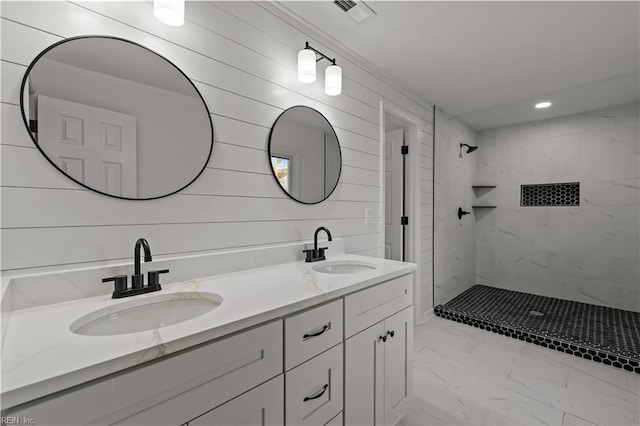 bathroom with double vanity, marble finish floor, a stall shower, and a sink