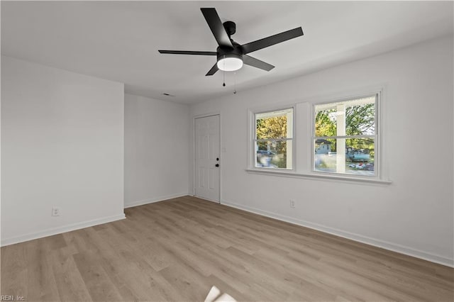 empty room with baseboards, a ceiling fan, and light wood-style flooring