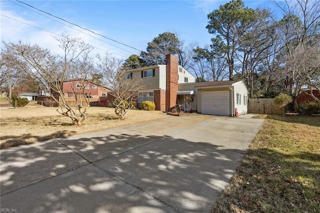 view of front of house featuring an attached garage, driveway, a chimney, and fence