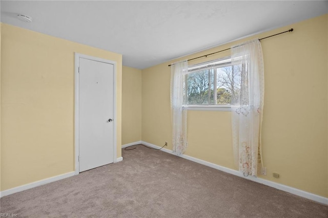 carpeted spare room featuring baseboards