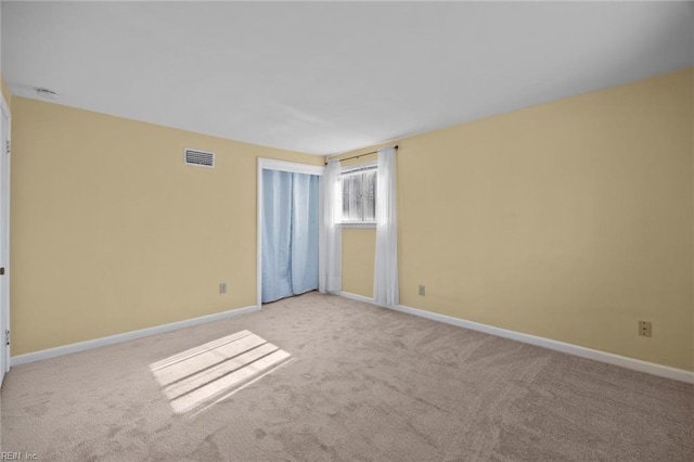 carpeted spare room with visible vents and baseboards