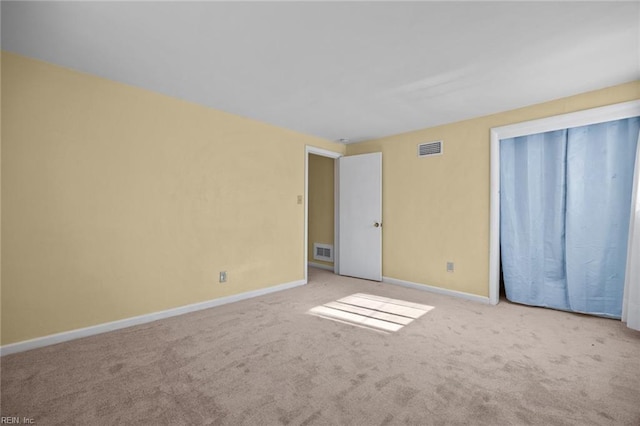 empty room featuring carpet, visible vents, and baseboards