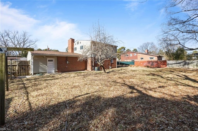 rear view of house featuring a chimney and fence