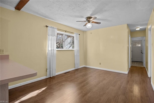 spare room featuring wood finished floors, visible vents, a textured ceiling, and ceiling fan