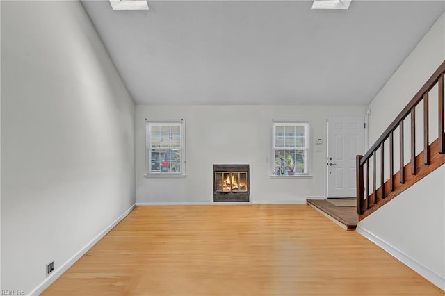 unfurnished living room with a glass covered fireplace, wood finished floors, baseboards, and stairway