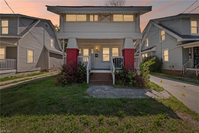 view of front facade with brick siding, a front yard, and covered porch