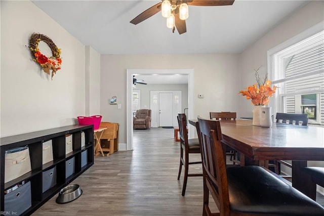 dining space featuring baseboards, a ceiling fan, and wood finished floors