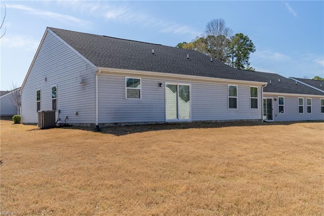 rear view of house featuring a lawn, a shingled roof, and central AC unit