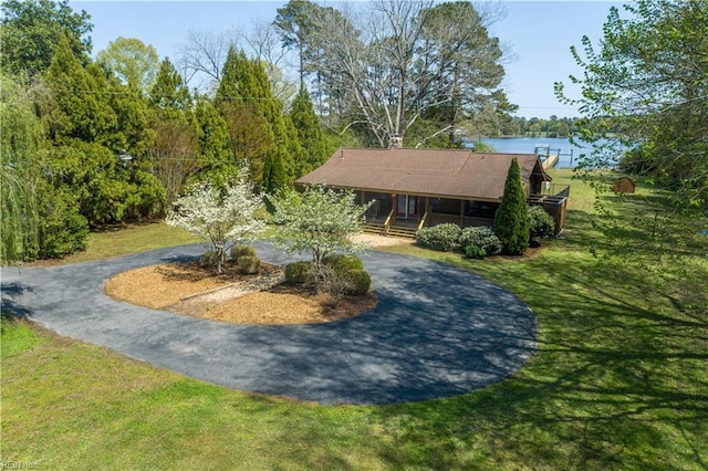 view of home's community with a lawn, a water view, and curved driveway