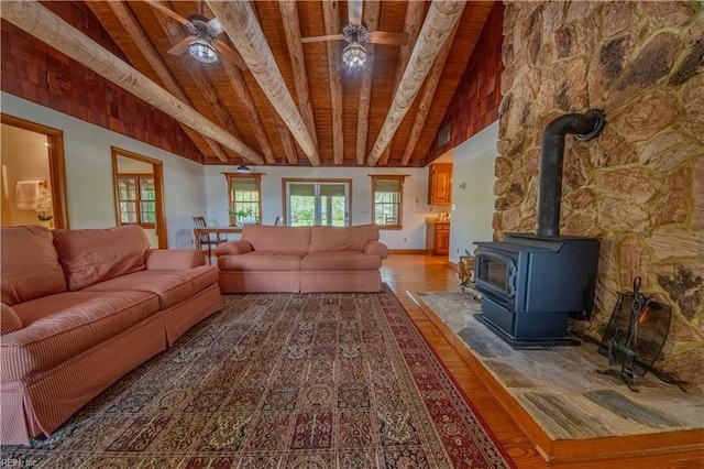 living room with wood ceiling, a wood stove, wood finished floors, and beamed ceiling