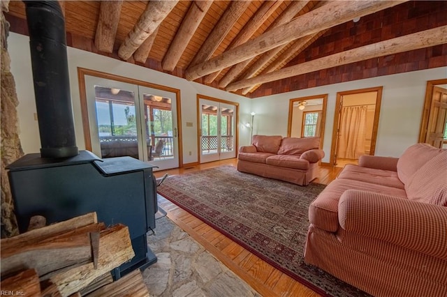 living area featuring beamed ceiling, french doors, a wealth of natural light, and a wood stove