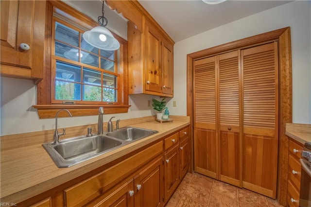 kitchen with stove, light countertops, a sink, light tile patterned flooring, and brown cabinetry
