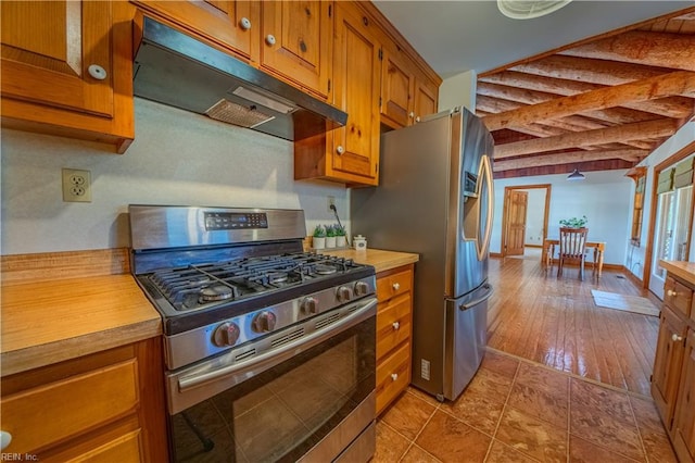 kitchen featuring under cabinet range hood, light countertops, beamed ceiling, brown cabinetry, and appliances with stainless steel finishes