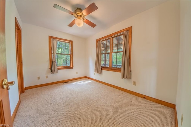 carpeted empty room featuring visible vents, baseboards, and ceiling fan