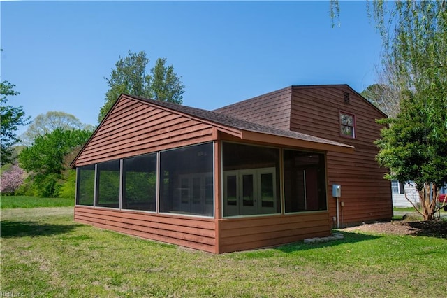 back of house with a lawn, a shingled roof, and a sunroom