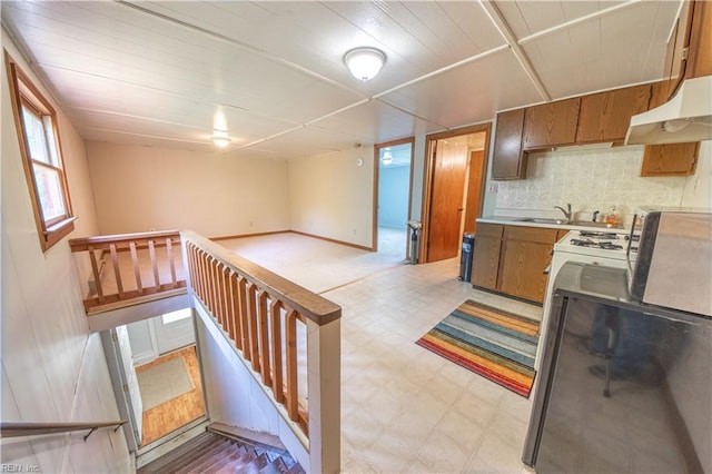 kitchen with decorative backsplash, open floor plan, light floors, light countertops, and under cabinet range hood
