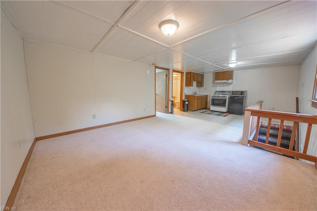 finished below grade area featuring refrigerator, light carpet, and baseboards