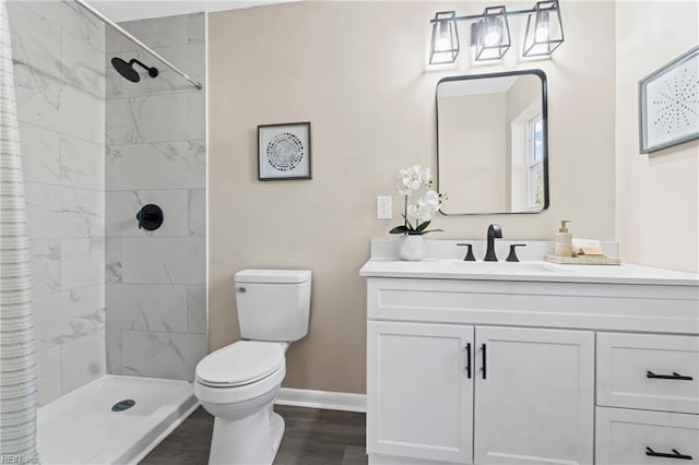 full bathroom featuring wood finished floors, vanity, baseboards, toilet, and tiled shower