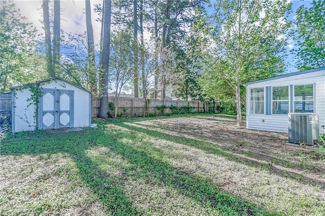 view of yard featuring a storage unit, an outbuilding, central AC, and fence
