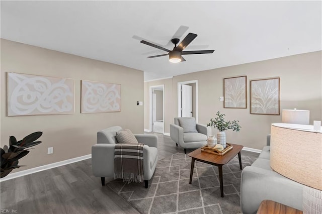 living area featuring dark wood-type flooring, baseboards, and ceiling fan