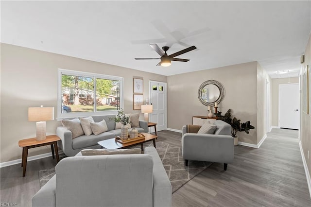 living area featuring attic access, ceiling fan, baseboards, and wood finished floors