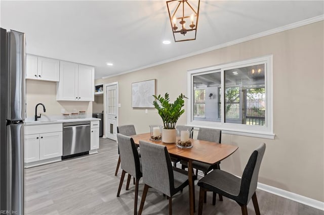 dining space featuring light wood-type flooring, crown molding, baseboards, and a notable chandelier