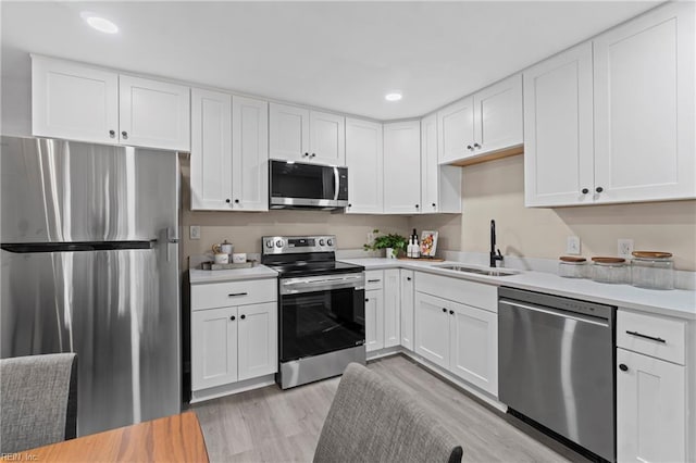 kitchen featuring white cabinets, appliances with stainless steel finishes, a sink, and light countertops