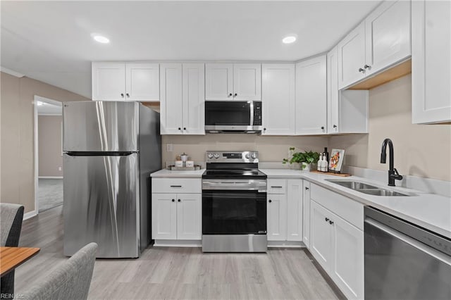 kitchen featuring a sink, light wood-type flooring, stainless steel appliances, light countertops, and white cabinets