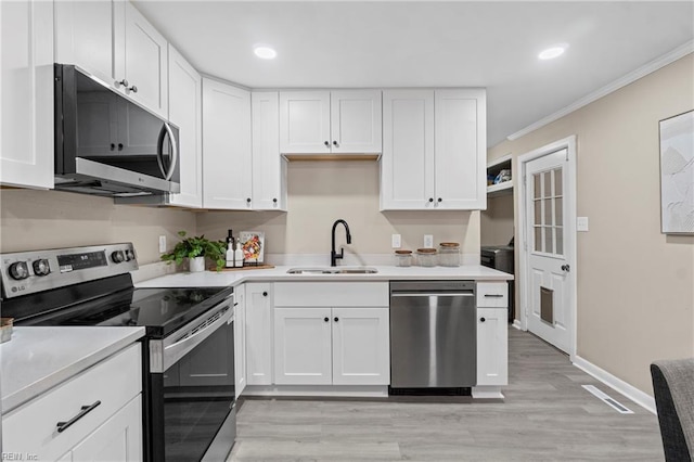 kitchen featuring white cabinets, stainless steel appliances, light wood-style flooring, and a sink