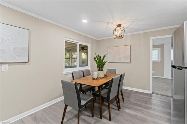 dining space featuring wood finished floors, baseboards, a chandelier, and crown molding