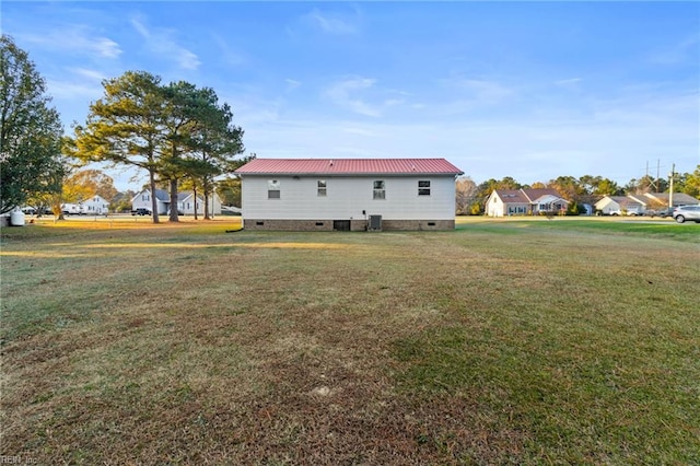 rear view of house with a yard, crawl space, and metal roof