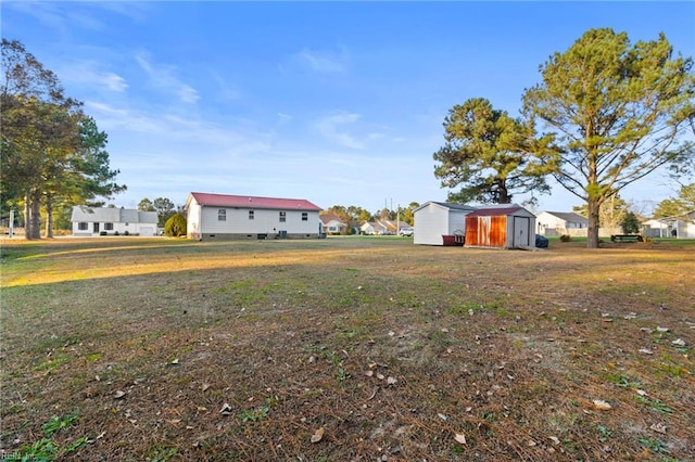 view of yard featuring a storage unit, an outbuilding, and a residential view