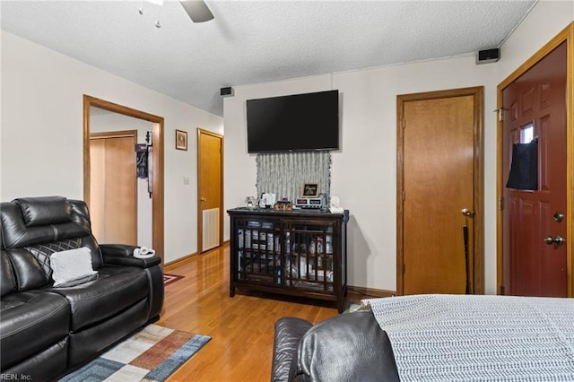 bedroom featuring ceiling fan, visible vents, a textured ceiling, and light wood finished floors