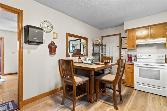 kitchen featuring brown cabinetry, under cabinet range hood, a textured ceiling, and electric stove