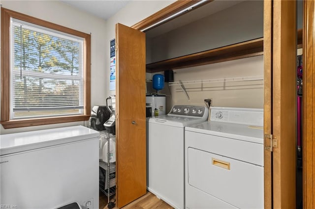 washroom featuring washing machine and dryer, light wood-style floors, electric water heater, and laundry area