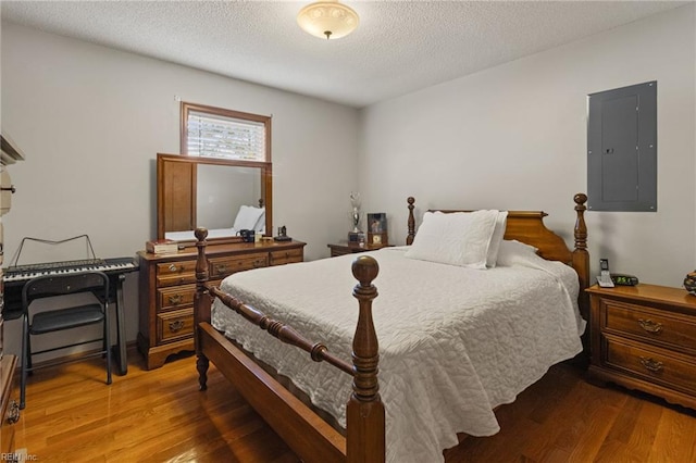 bedroom with wood finished floors, electric panel, and a textured ceiling