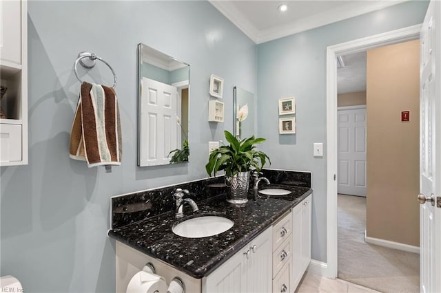 bathroom with double vanity, baseboards, a sink, and ornamental molding