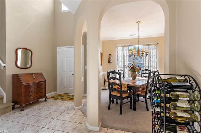 dining space featuring light tile patterned floors, arched walkways, a notable chandelier, and baseboards
