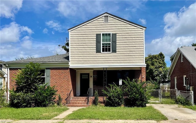 view of front of home with brick siding, a porch, and fence